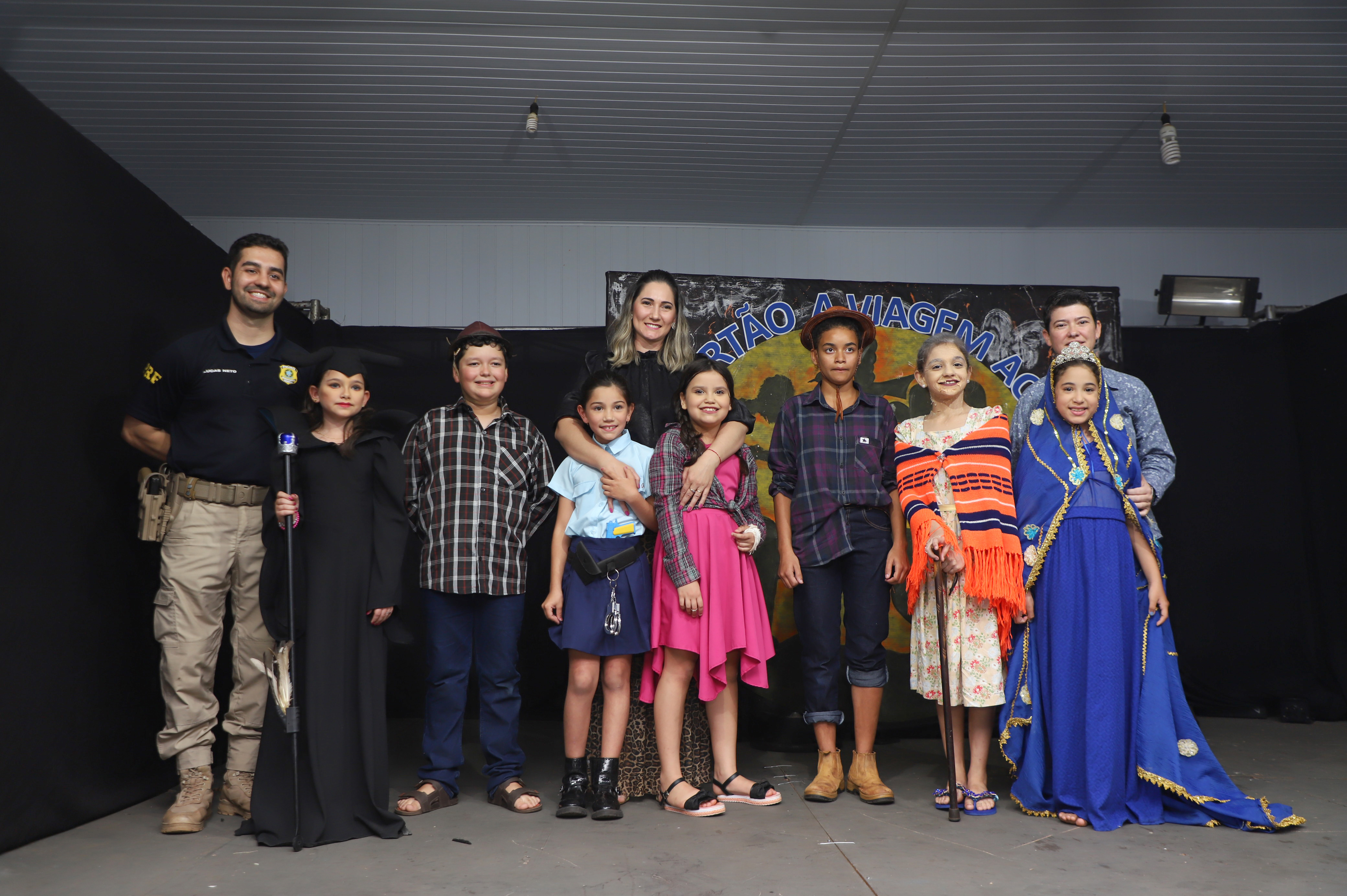 Inspetor da PRF, Lucas Neto, professora Ana Cláudia e responsável pelo departamento de Cultura, Jaqueline Souza, posam junto ao elenco mirim - Foto: Prefeitura de Batayporã